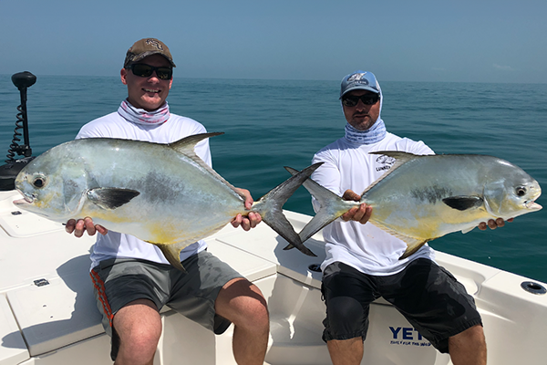 Jeff and a guest displaying their catch on a boat