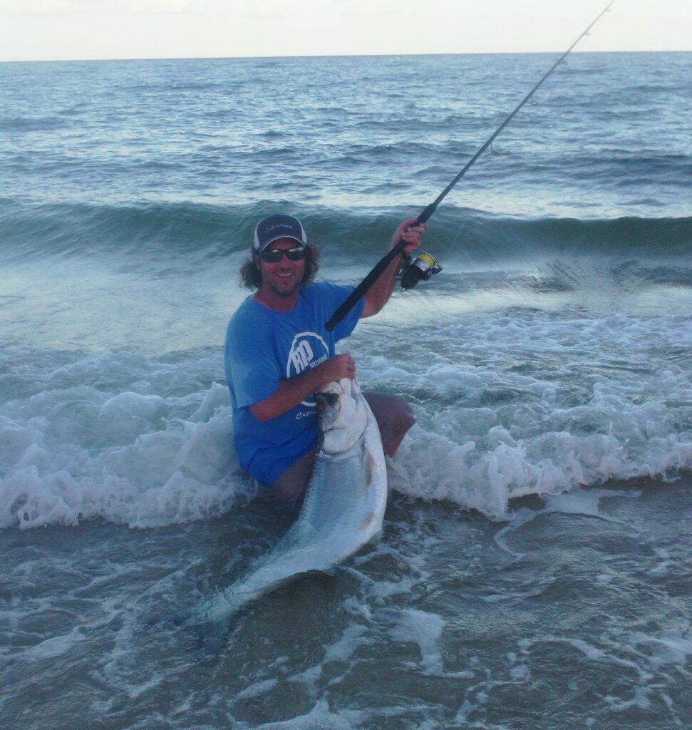 Fisherman kneeling on a boat with a fish on the side near Miami