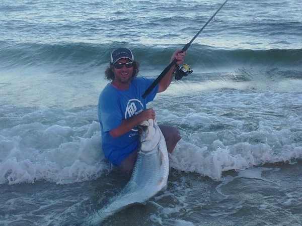 Fisherman kneeling on a boat with a fish on the side near Miami